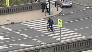 Zdjęcie obrazuje wykroczenie rowerzysty, który przejeżdża przez przejście dla pieszych nie zsiadając z bicykla.