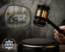 Na zdjęciu grafika obrazującą młotek osoby prowadzącej licytację, widać tez lusterko samochodowe a w nim odbicie pojazdu z wypadku.